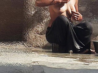 Indian sister-in-law is bathing in the open courtyard of the house, putting a finger in her burrow and rubbing the body, sister-in-law is washing the bathroom.