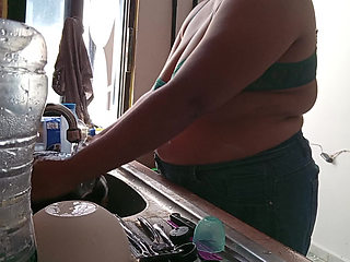 Mother-in-law cleans in the kitchen in bra