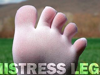 Feet in Cute White Socks with Jeans on the Grass Field